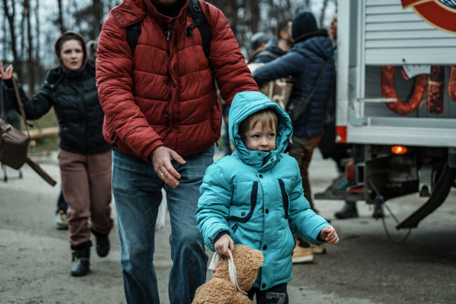 Parent guides small Ukrainian child.