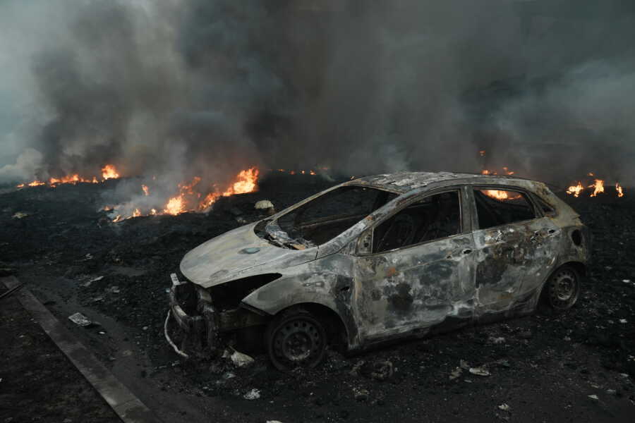 Destroyed car and burning landscape in Ukraine.