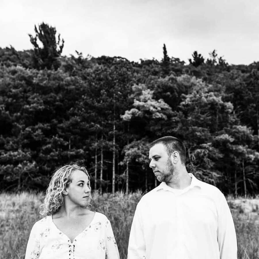 husband and wife stand next to each other and look to one another