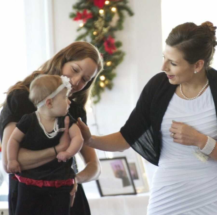 mom holding her baby while her friend greets here