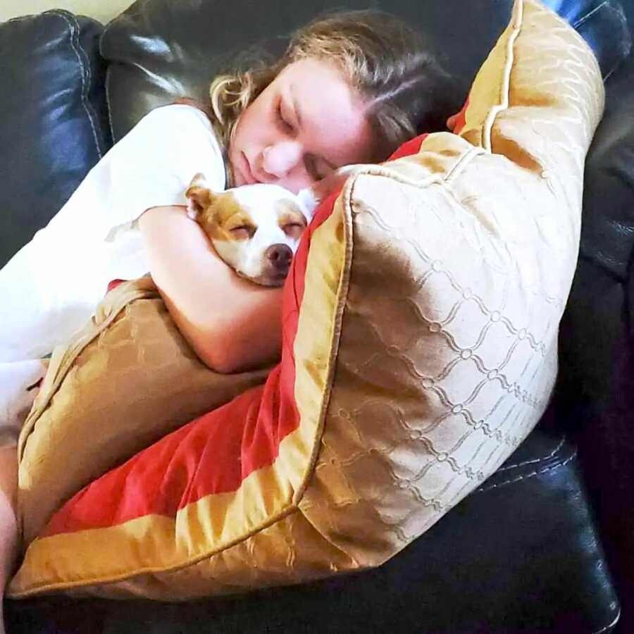 teenage daughter cuddles up on the couch with her dog