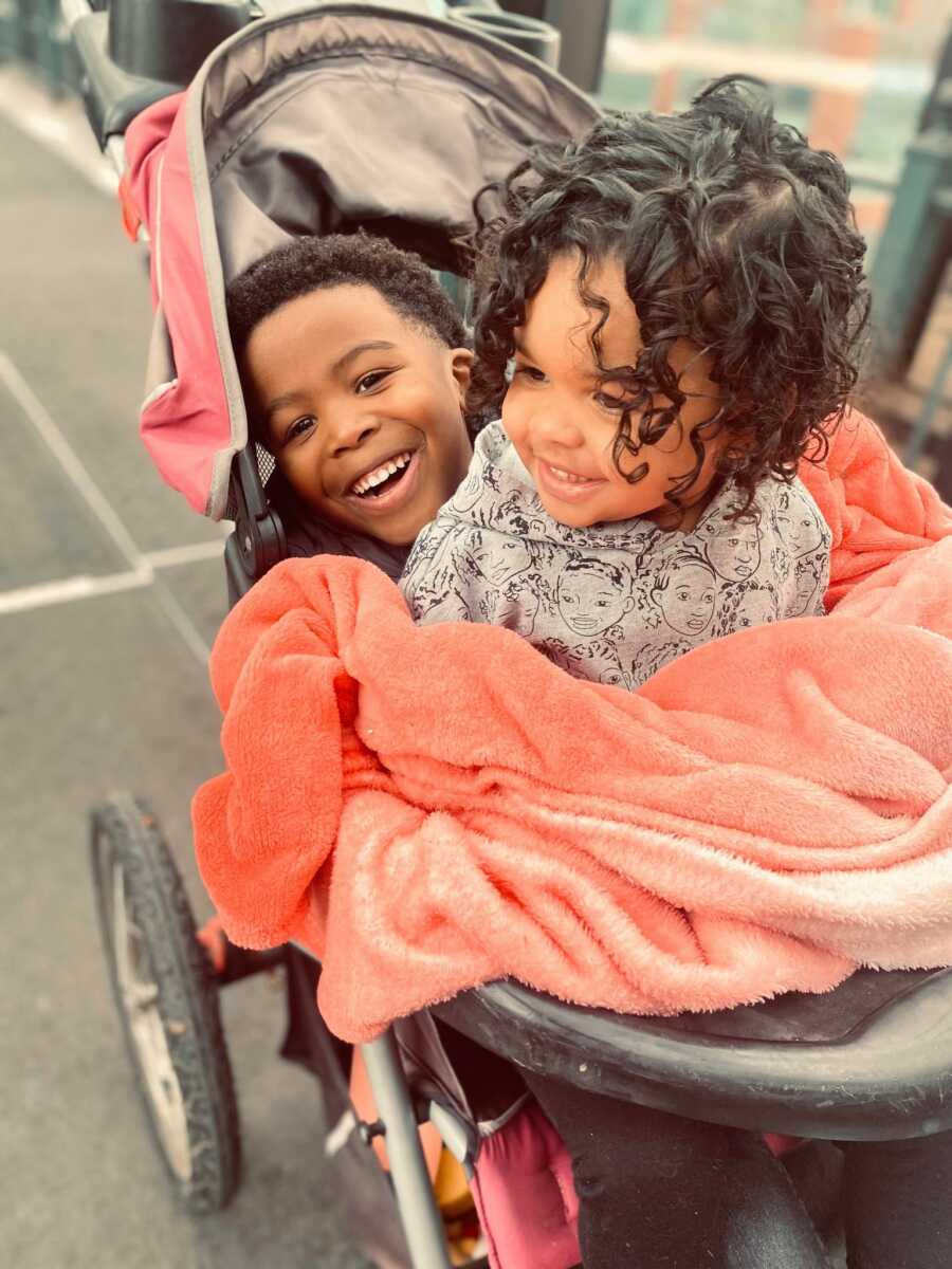 siblings in a stroller together smiling and laughing