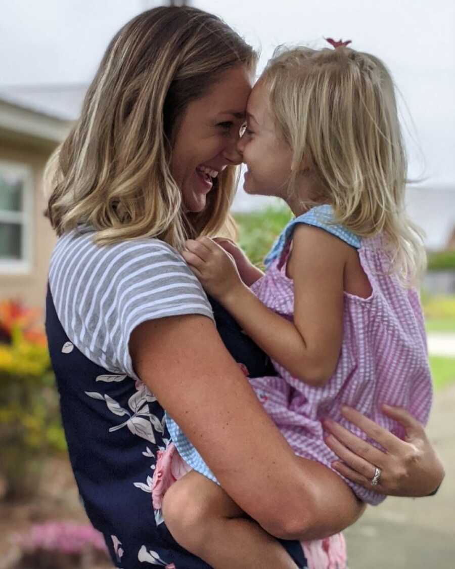 woman holding her daughter while smiling and laughing