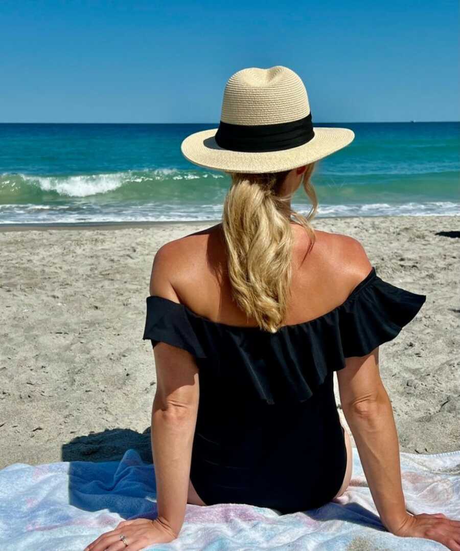 woman sitting on the beach facing the water