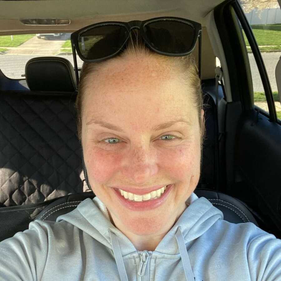 woman taking a selfie in her car with sunglasses on her head