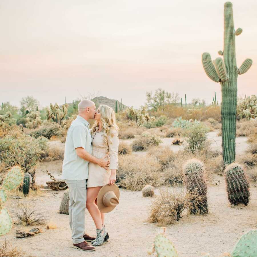 Couple shares a sweet kiss while taking desert-themed engagement photos while in Sedona, Arizona