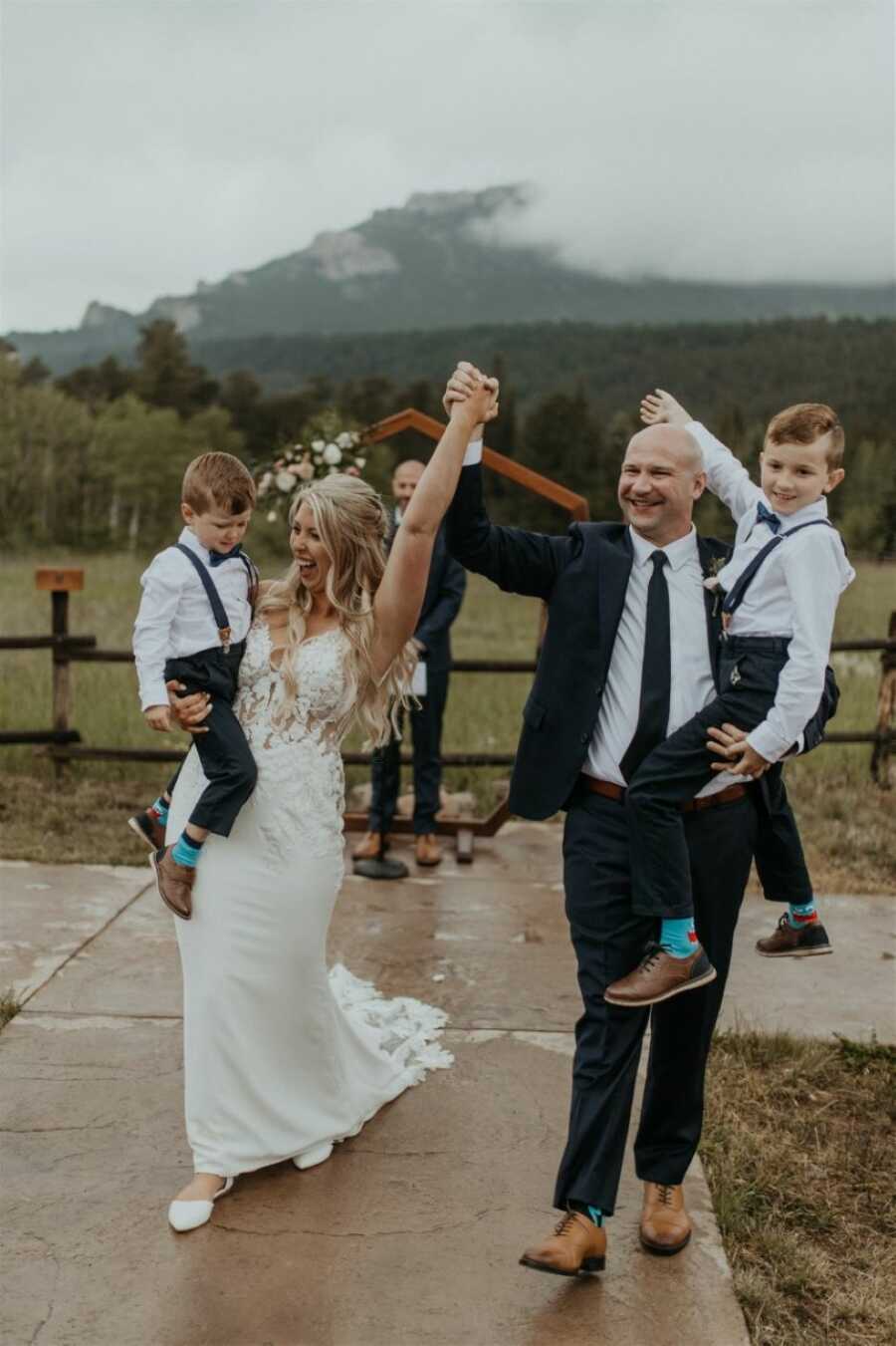 Newlyweds cheer while walking down the aisle as an official married couple with their two sons