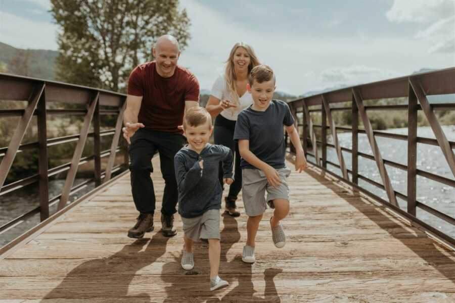 Newlyweds take silly photo chasing their two sons on a bridge during family photos