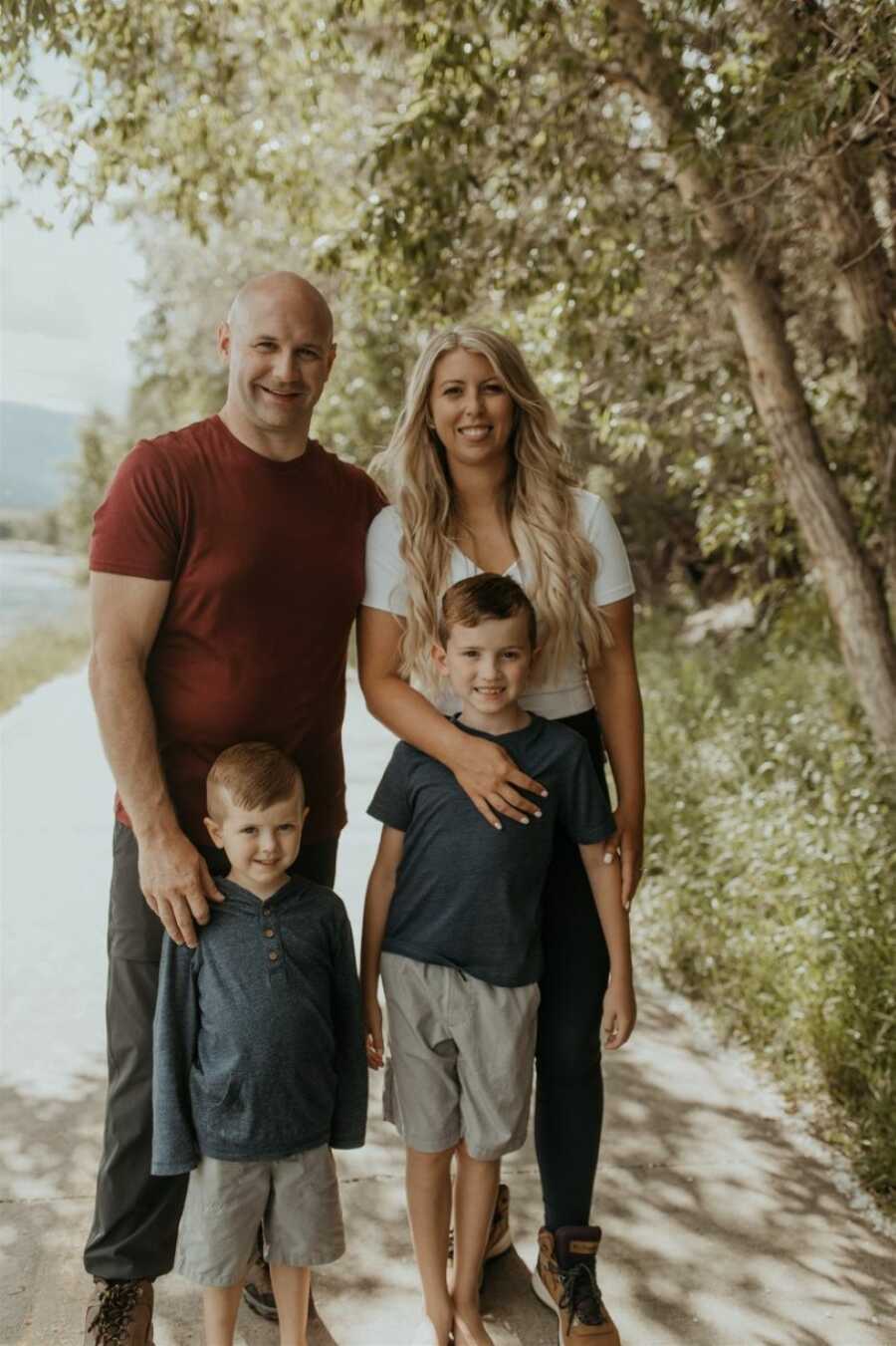 Family of four take photos together in a park while their sons wear matching outfits