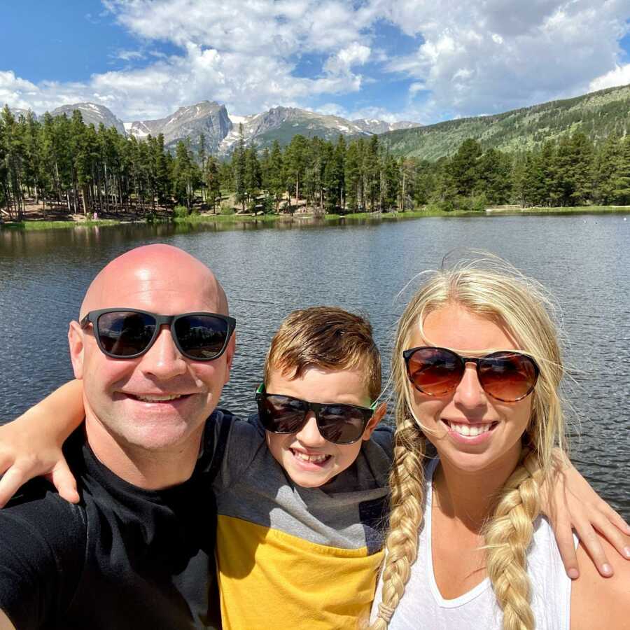 Couple take a selfie with one of their sons while enjoying time together out on a lake