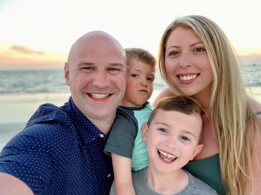 Blended family take a silly selfie together while enjoying the sunset on a beach