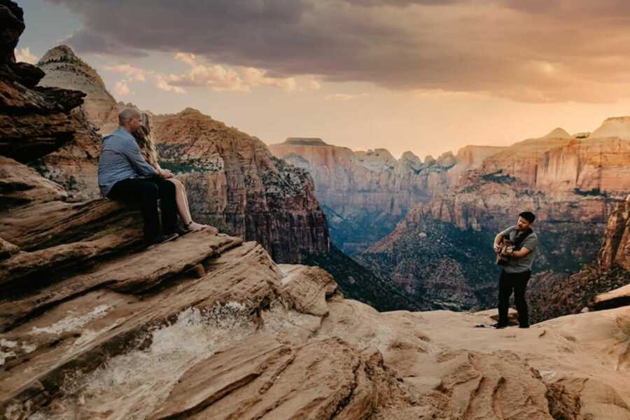 Artist Dave Tate plays guitar for a newly engaged couple in Zion National Park