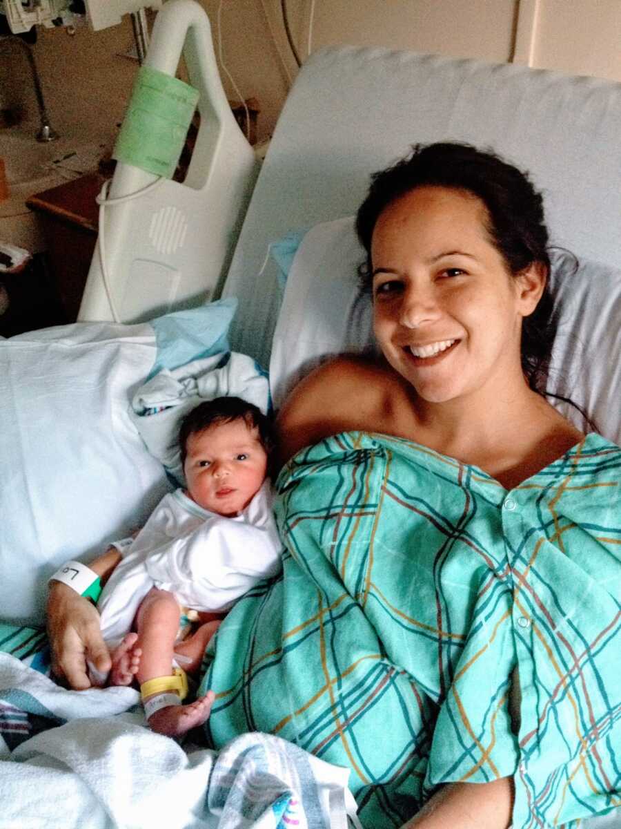 Woman and newborn sit up in hospital bed together after an emergency C-section