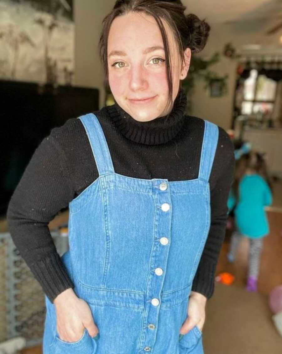 Mom of 4 takes a photo in a black turtleneck with denim overalls