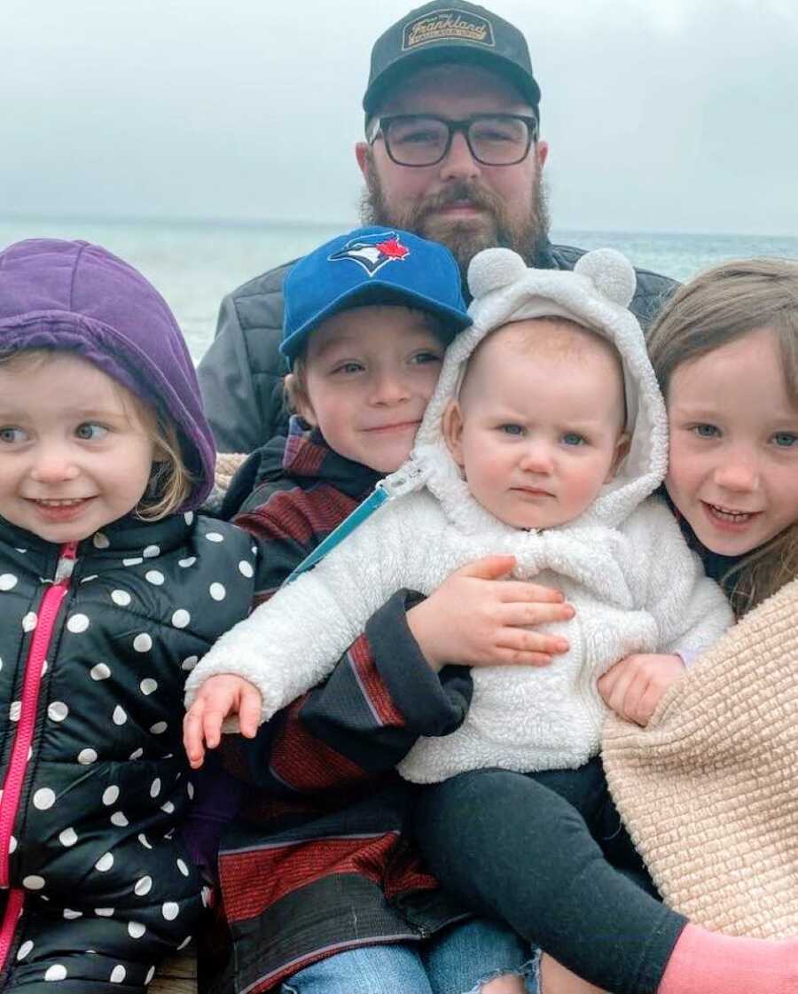 Mom takes a photo of her husband and four kids while enjoying a cold beach day
