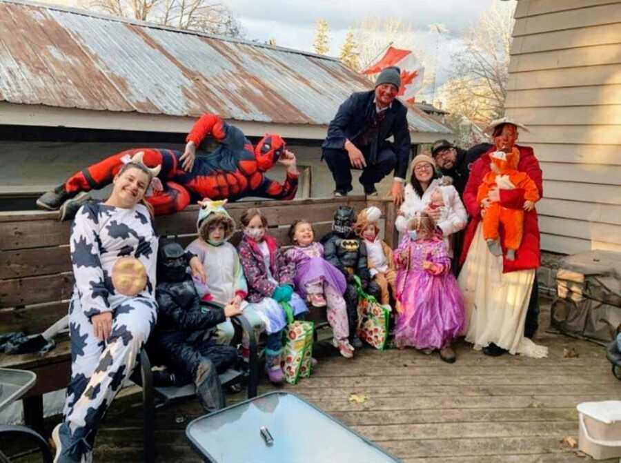 Two families take a group photo together dressed in Halloween costumes