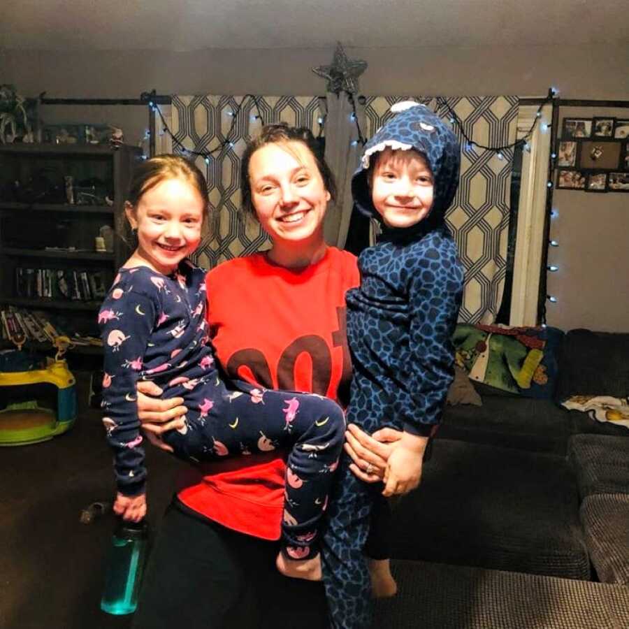 Mom smiles big while holding her two oldest kids on each hip