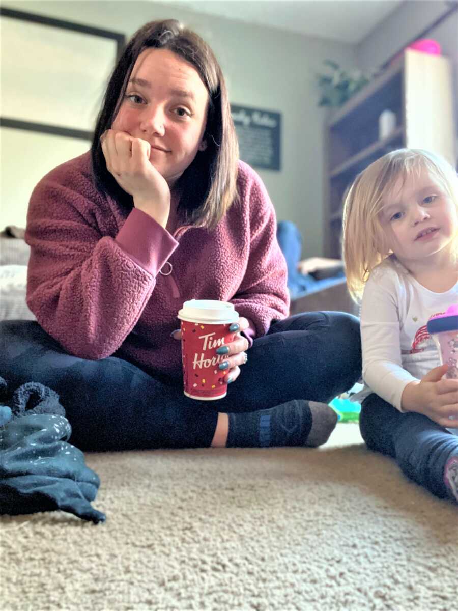 Mom sitting next to her toddler girl holding a cup of coffee