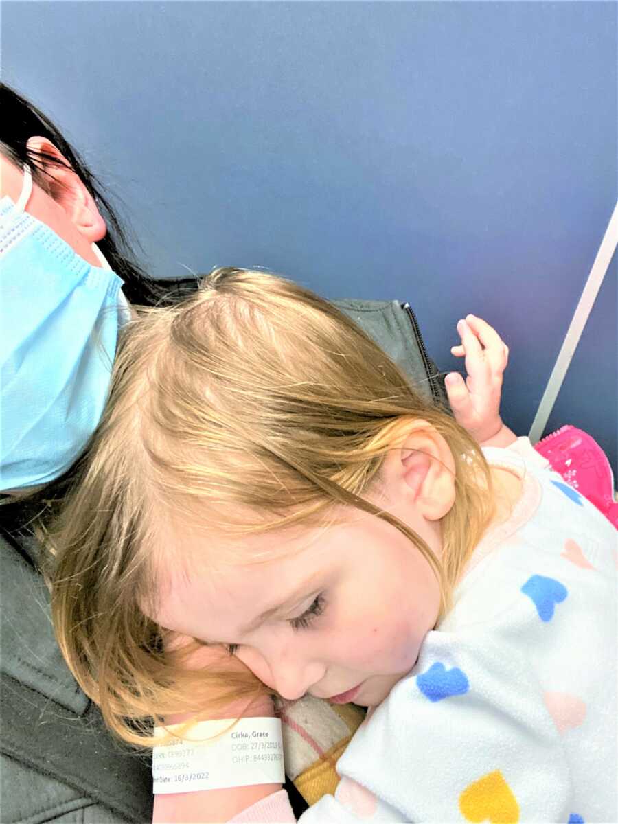 mom holding her toddler girl at the doctor's