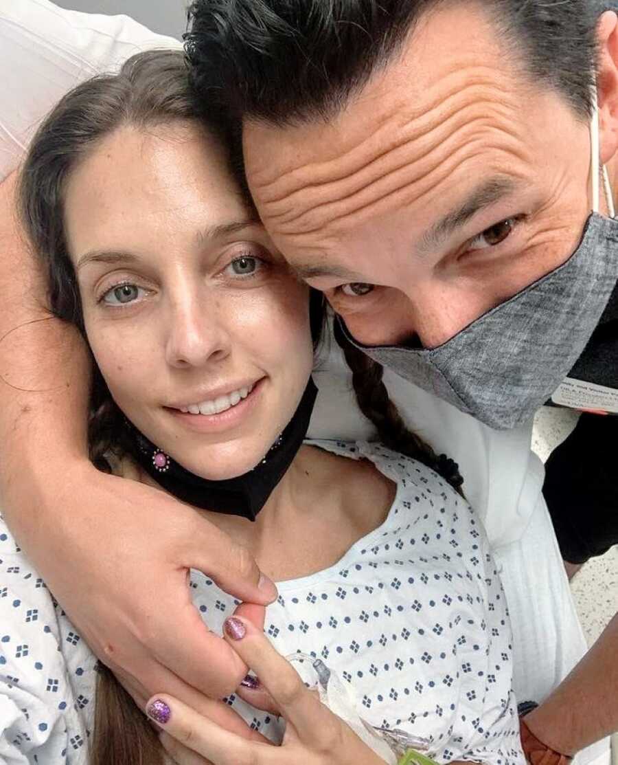 Couple hug and take a selfie together while the woman is in the hospital
