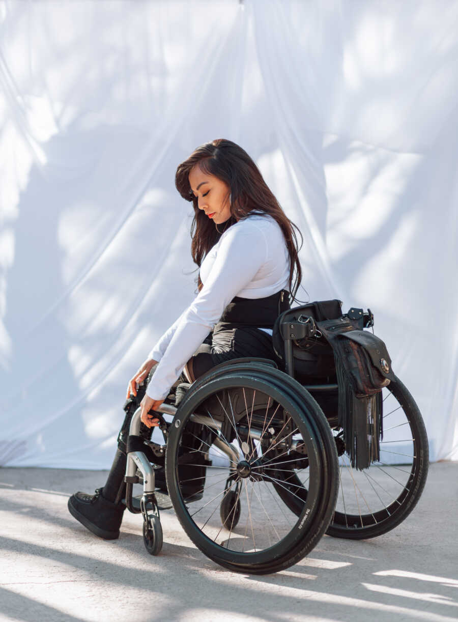 Woman paralyzed from Transverse Myelitis takes a photo looking down at her legs while in her wheelchair