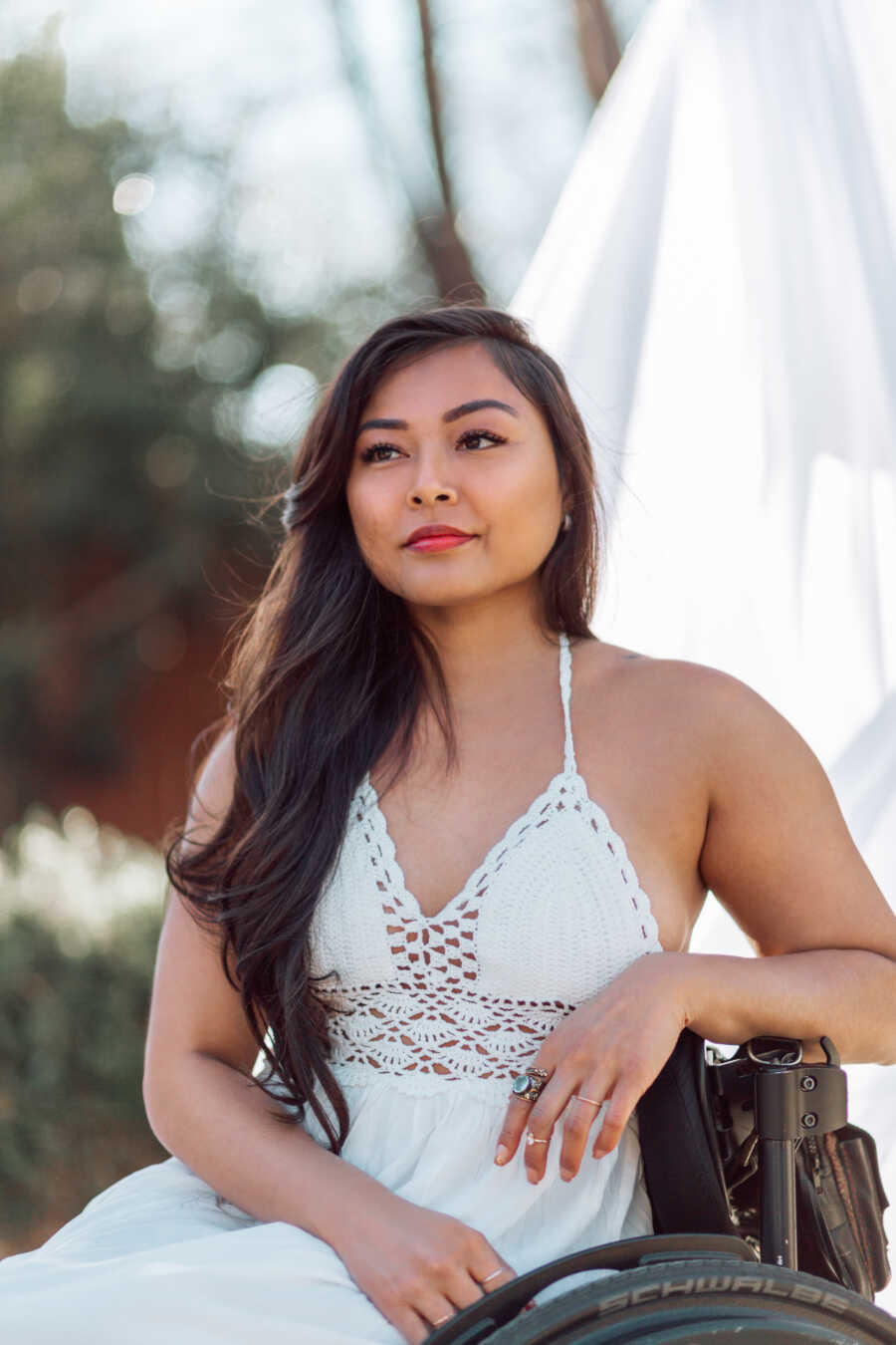 Woman in crocheted white top looks peaceful while sitting in her wheelchair