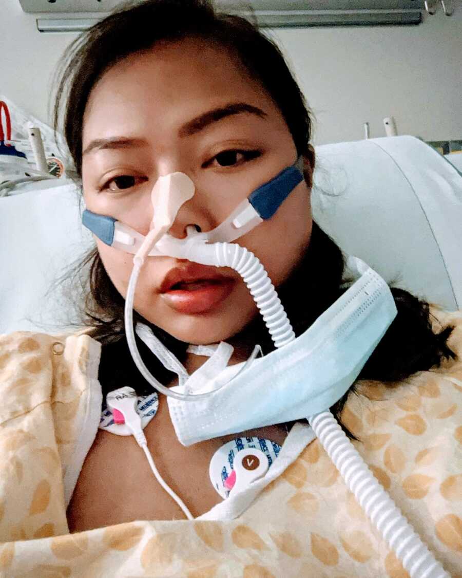 Woman with Transverse Myelitis looks scared in hospital selfie with neck brace and wires connected all over her