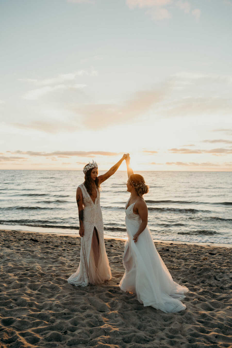 Wedding photography of Lesbian couple wearing white dresses and dancing at the beach 