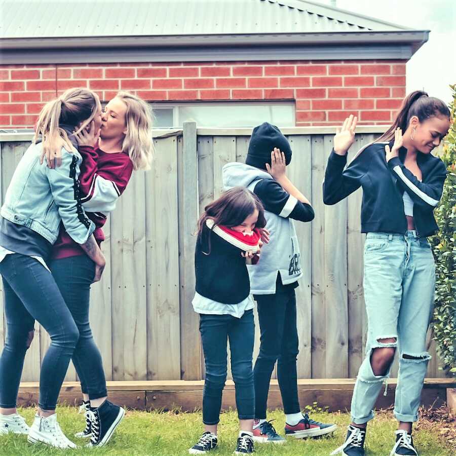 Lesbian mom kissing girlfriend while her kids look disgusted 