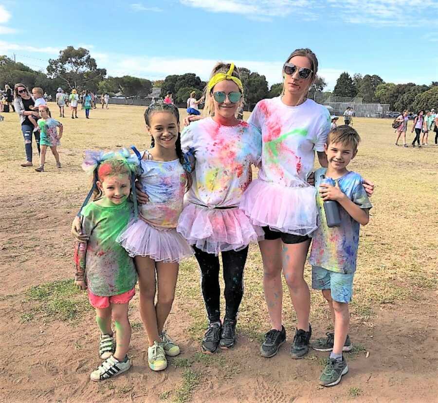 Mom with her three kids and her girlfriend with their clothes splashed painted at a festival