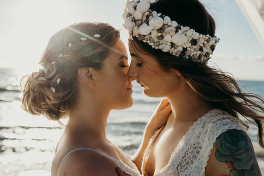 Wedding photography of Lesbian couple wearing white dresses and kissing at the beach 