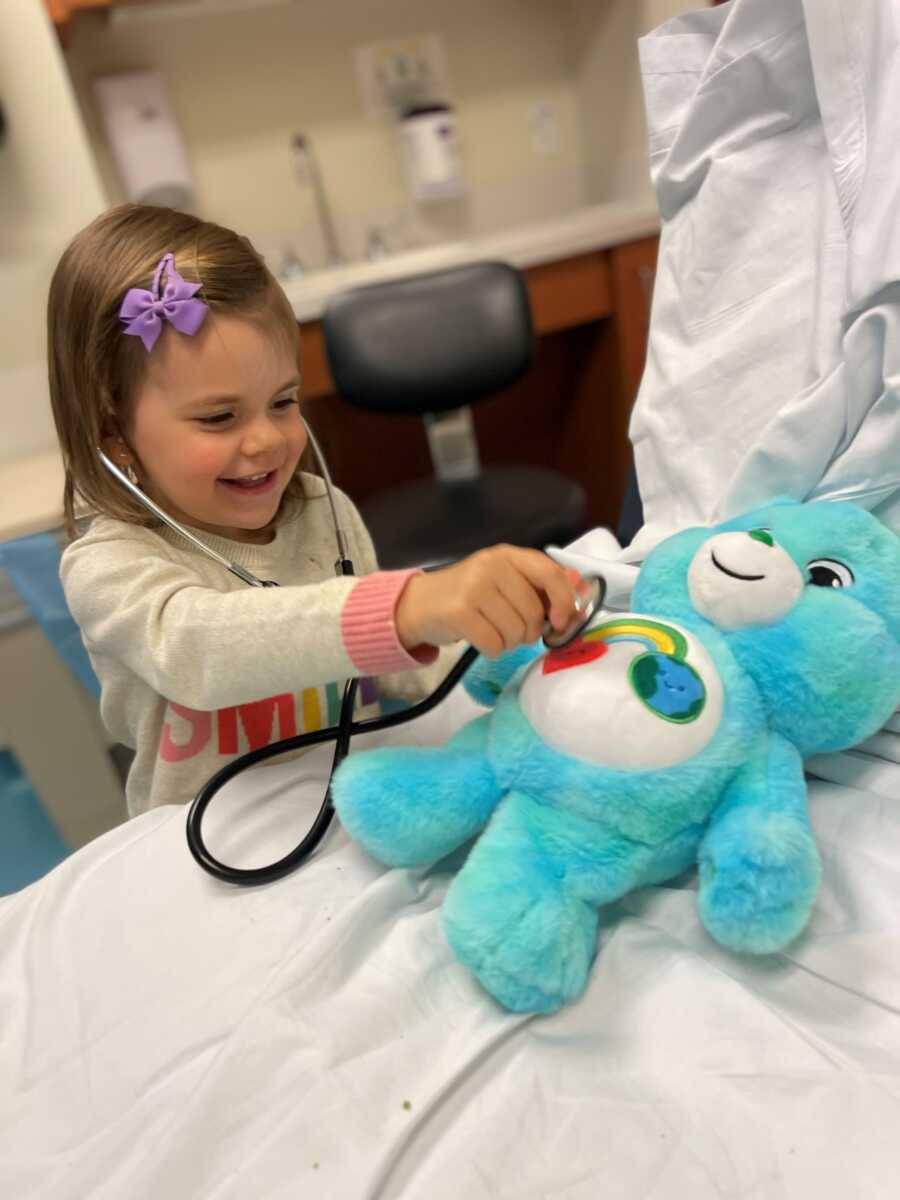 little girl checking the heart beat of the care bear