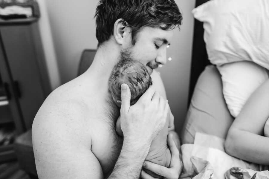 dad holding his newborn son onto his naked chest 