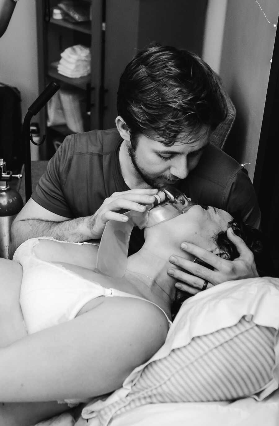 Husband putting an oxygen mask on her pregnant wife during childbirth 