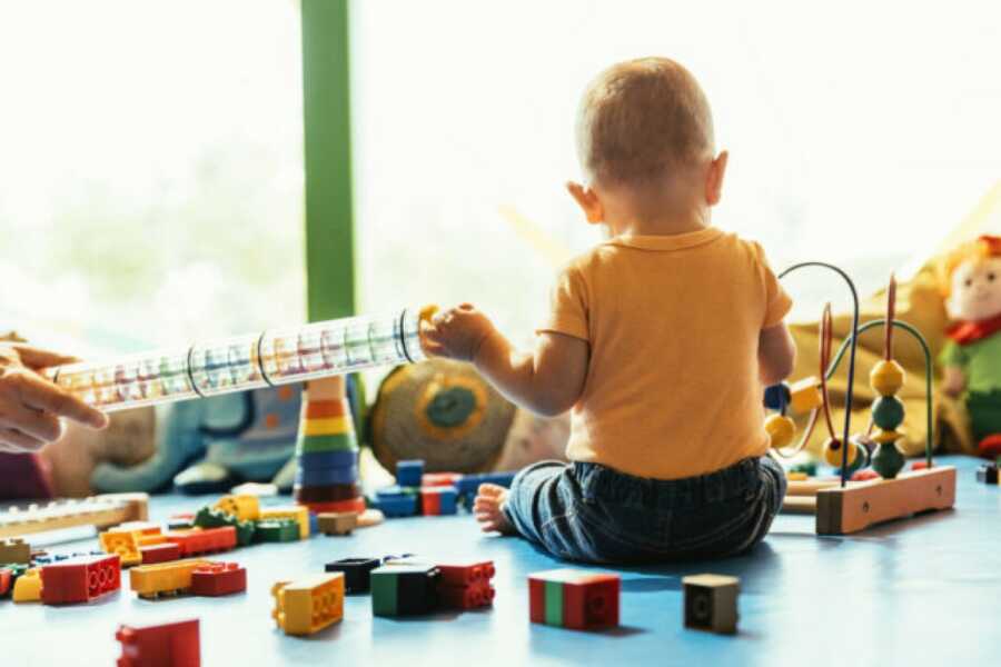 baby sitting on the floor at childcare playing