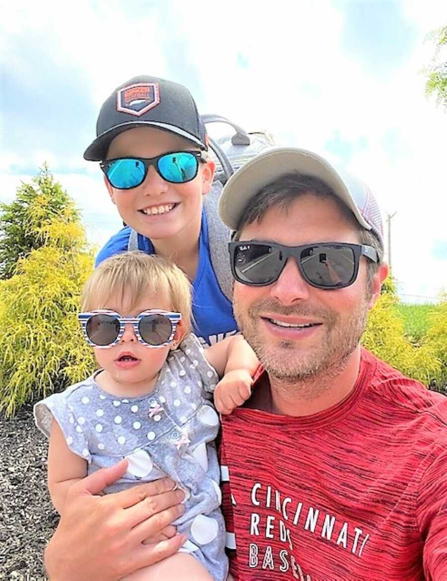 dad and their two kids all wearing sunglasses and summer clothing during vacation