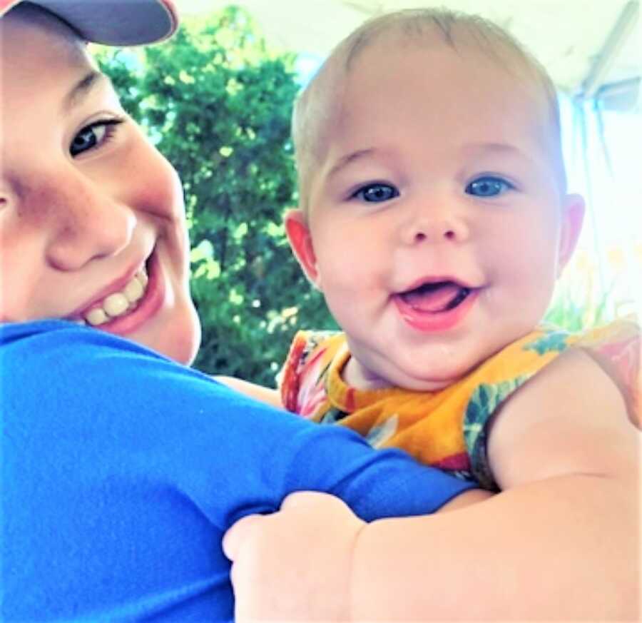 big brother carrying his little baby sister and smiling 