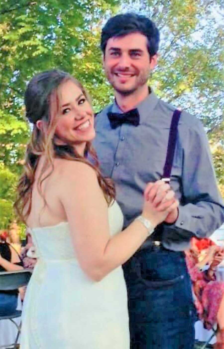 Couple smile and pose while dancing together at their wedding reception