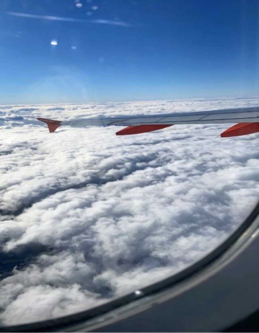 Woman flying back home takes a photo of the clouds in the sky outside of the window