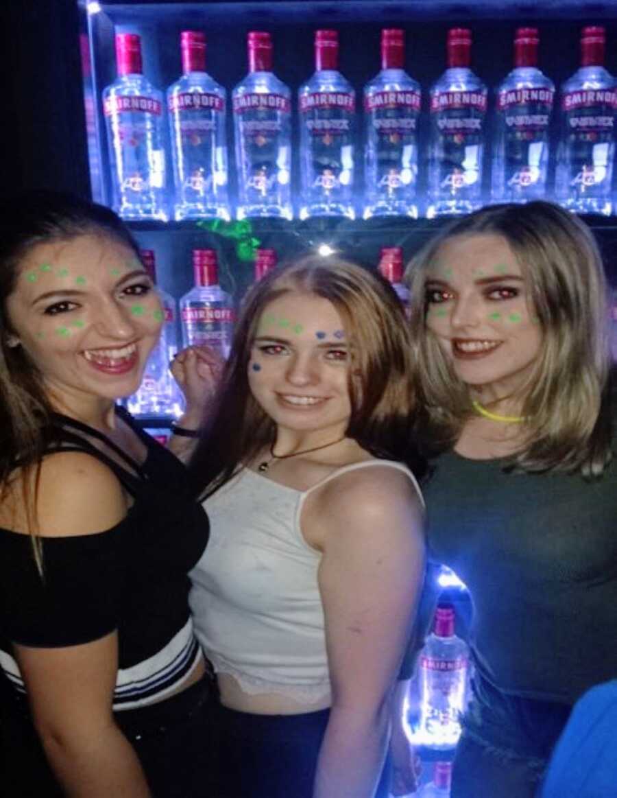 Group of college women take a photo at a bar with their faces painted