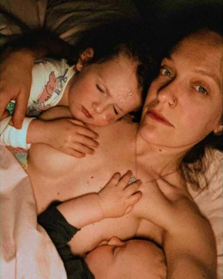 Mom cuddles with her two kids who fell asleep breastfeeding