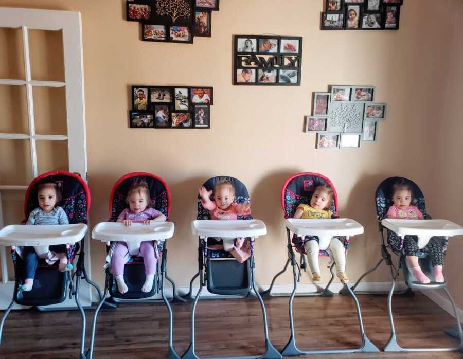 All-girl quintuplets sit in high chairs while waiting on their lunch
