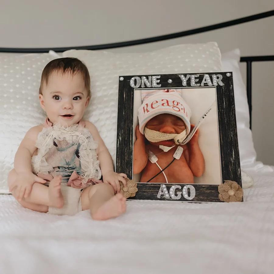 Reagan sits next a photo of herself as a newborn, showing how much she's grown in a year