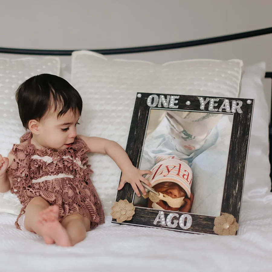 Zylar sits next a photo of herself as a newborn, showing how much she's grown in a year