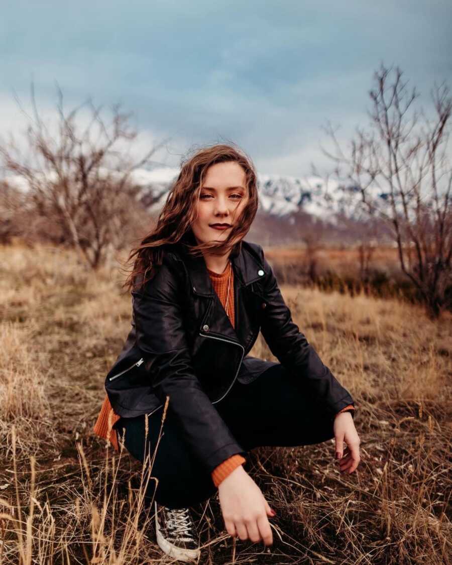 outdoors portrait of a woman kneeling on the floor with snowy mountains in the back