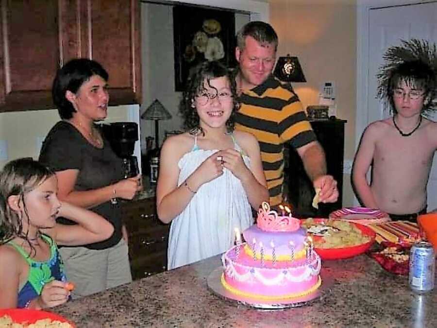 preteen girl celebrating her birthday with her parents and friends singing happy birthday with a princess themed cake