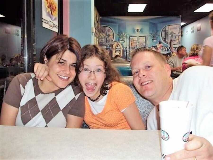 selfie of teenage girl with her mom and dad sitting at a restaurant 