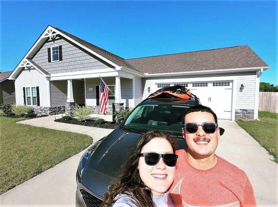 selfie of newly married couple outside of their house and their car 