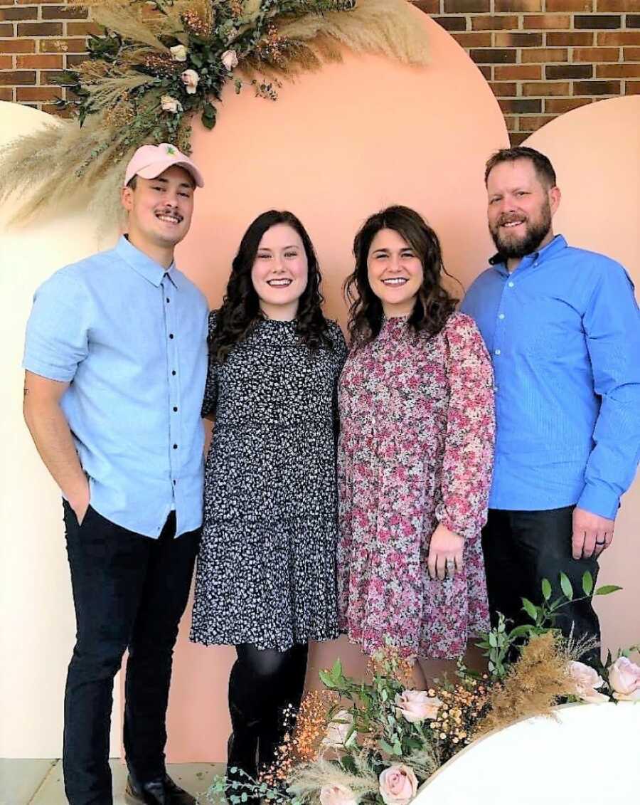 woman in her twenties standing in-between her parents and her husband 