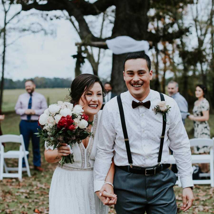 wedding picture of a bride and a groom walking down the isle in an outdoors wedding